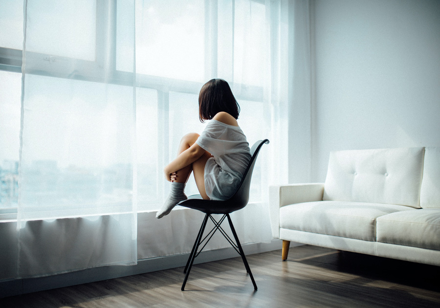 A girl sitting on a Chair up by a window